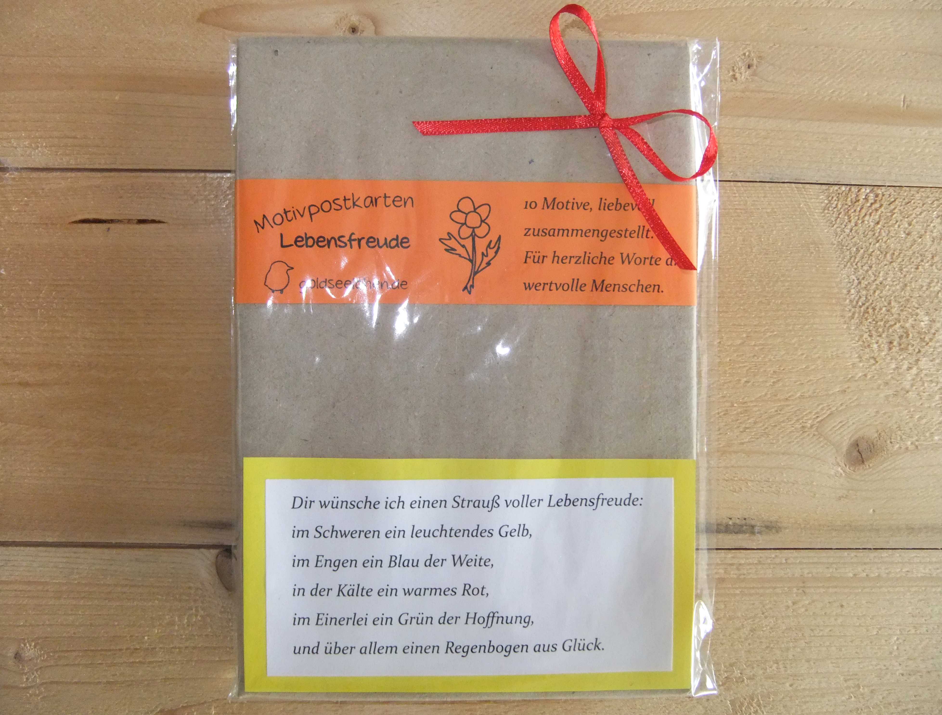 Geschenkig verpacktes Postkartenset mit Lebensfreude-Badezusatz und Spruch
